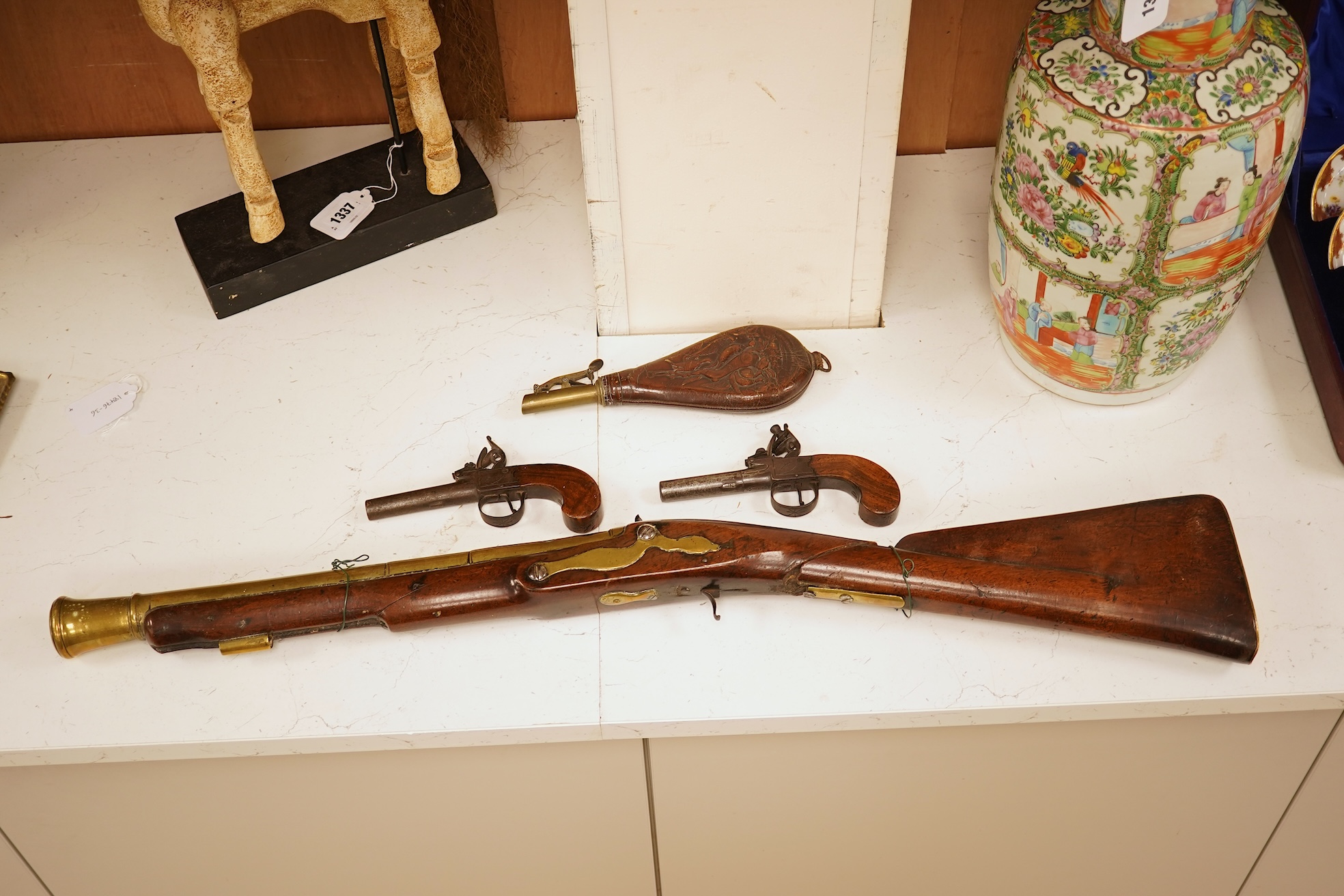 A pair of 19th century pocket pistols, shot flask and a brass musket, 81cm in length